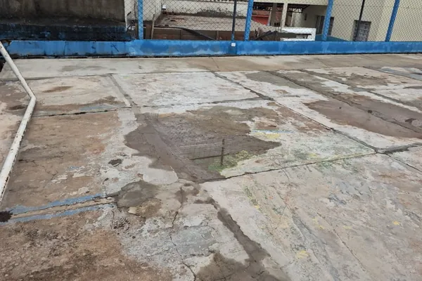Contrapiso trincado e desnivelado em placas. Praça com playground e quadra, São Thomé das Letras, MG.