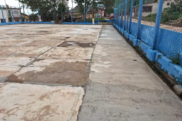 Juntas abertas no piso antigo. Praça com playground e quadra, São Thomé das Letras, MG.