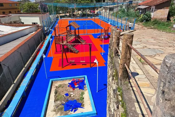 Área de recreação com brinquedos instalados. Praça com playground e quadra, São Thomé das Letras, MG.